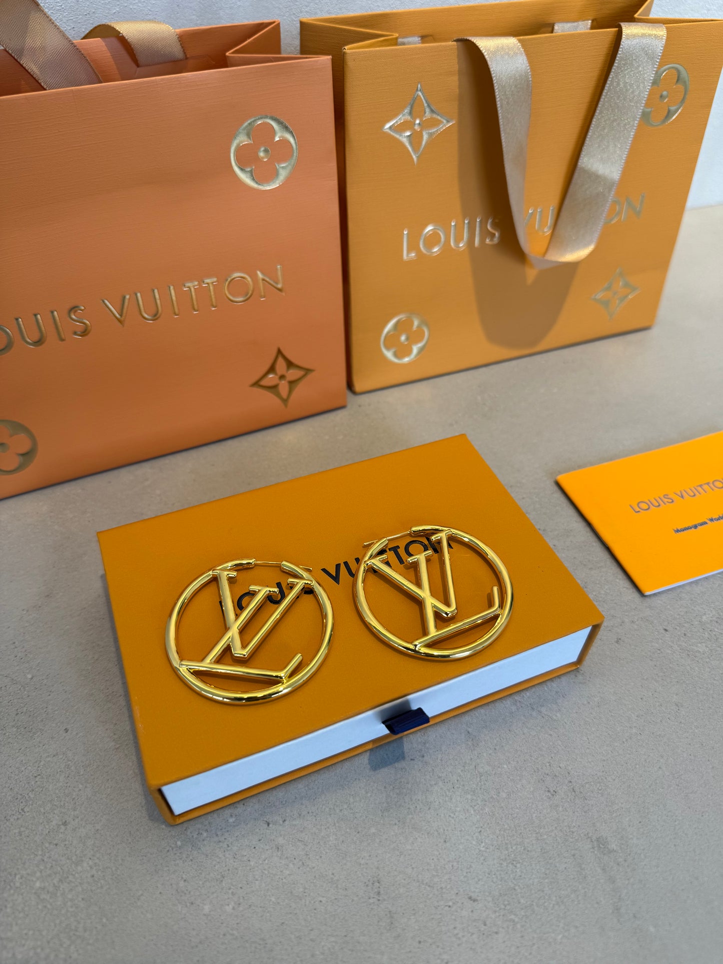 Aretes LV dorados grandes con diseño circular calado