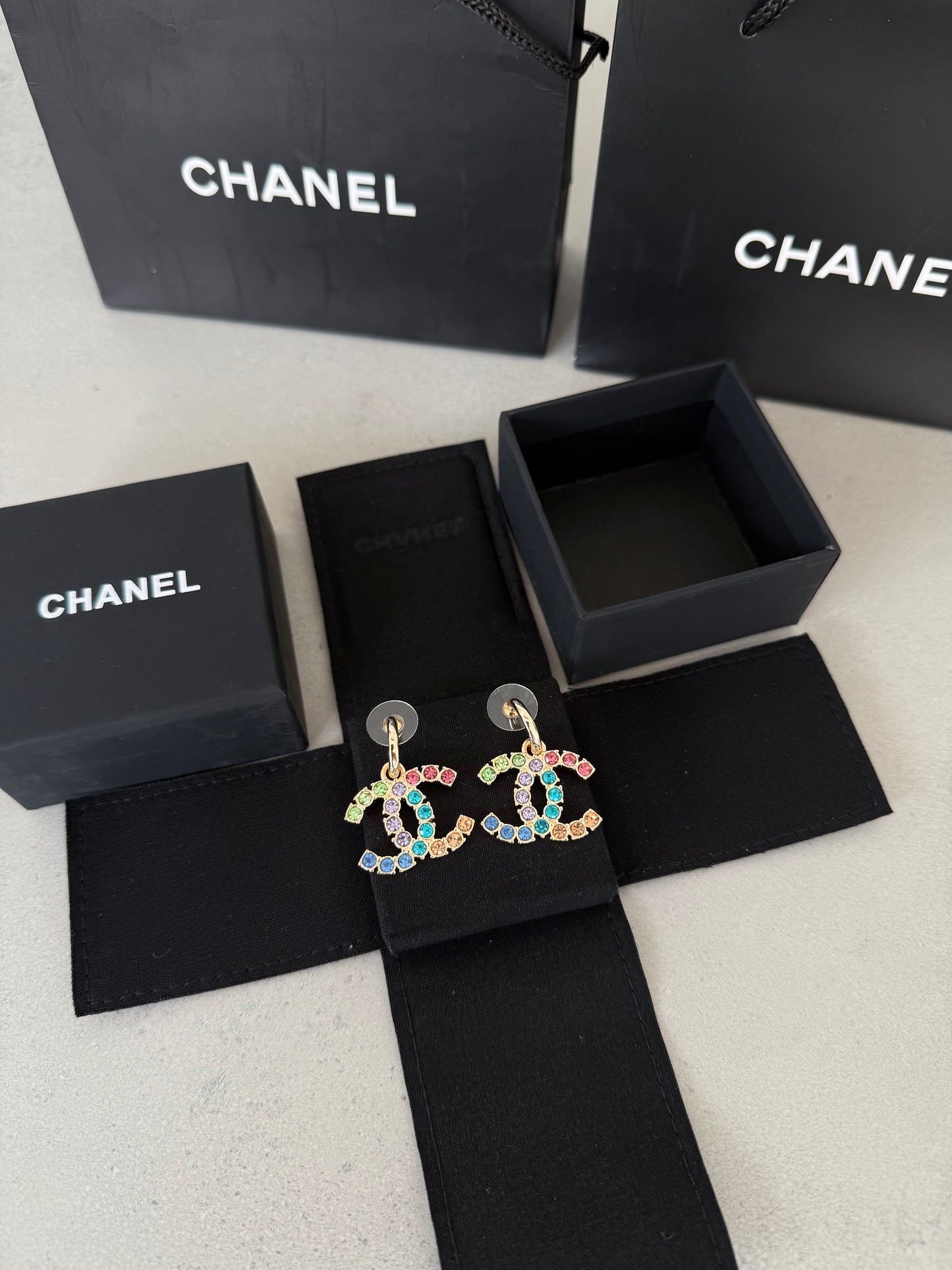 Aretes CC dorados con incrustaciones de colores