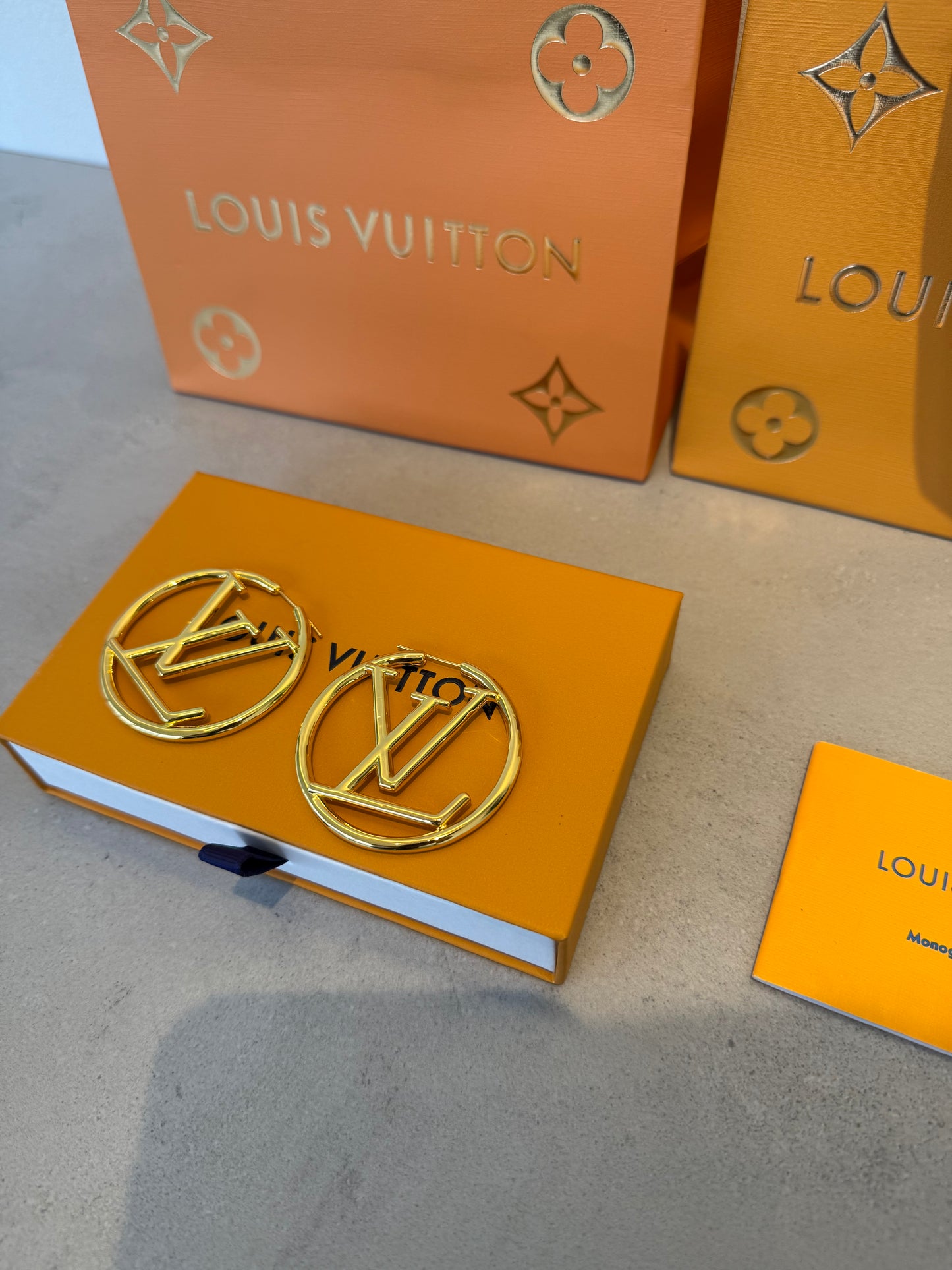Aretes LV dorados grandes con diseño circular calado