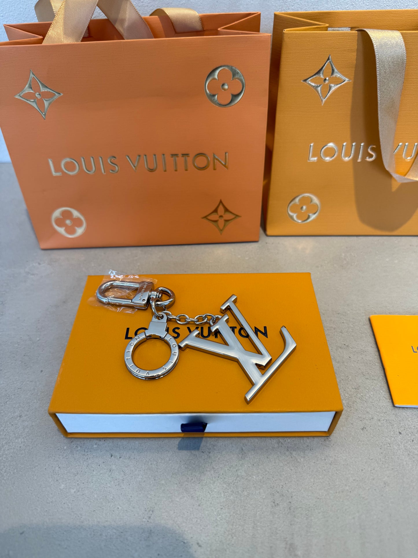 Llavero LV plateado con colgante grande del logo