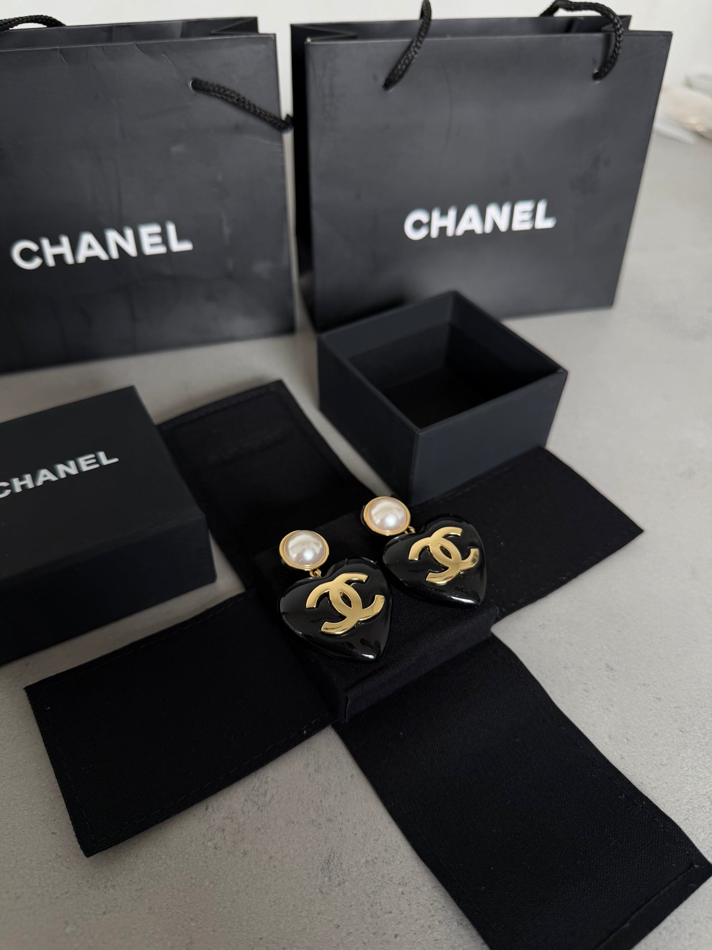 Aretes CC corazón negro con perla y logo dorado