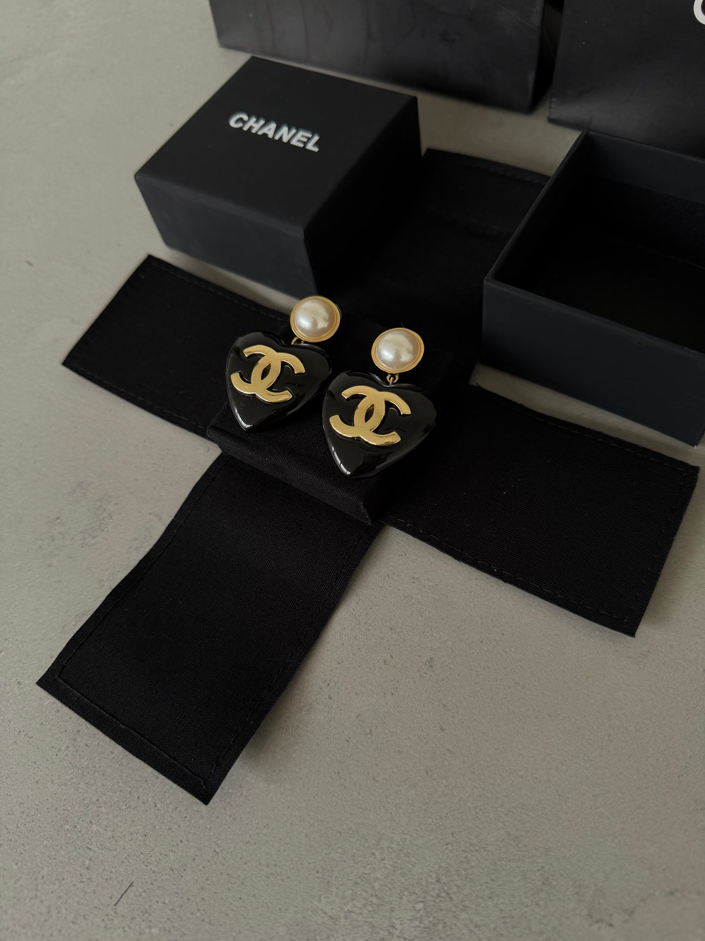 Aretes CC corazón negro con perla y logo dorado
