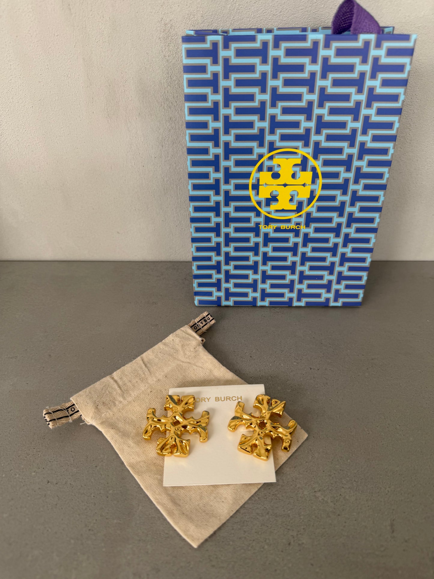 Aretes TB dorados con diseño de logo texturizado