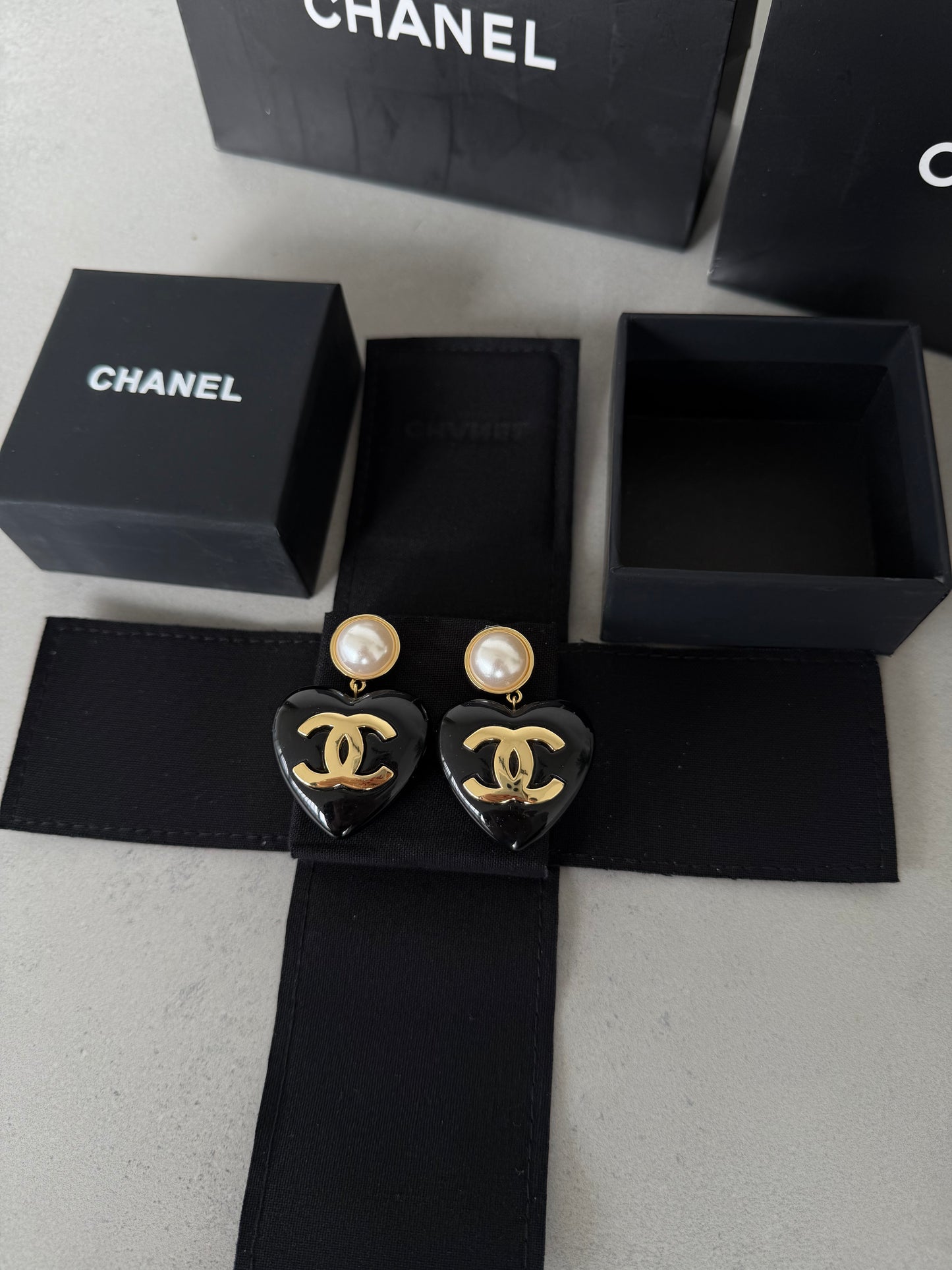 Aretes CC corazón negro con perla y logo dorado