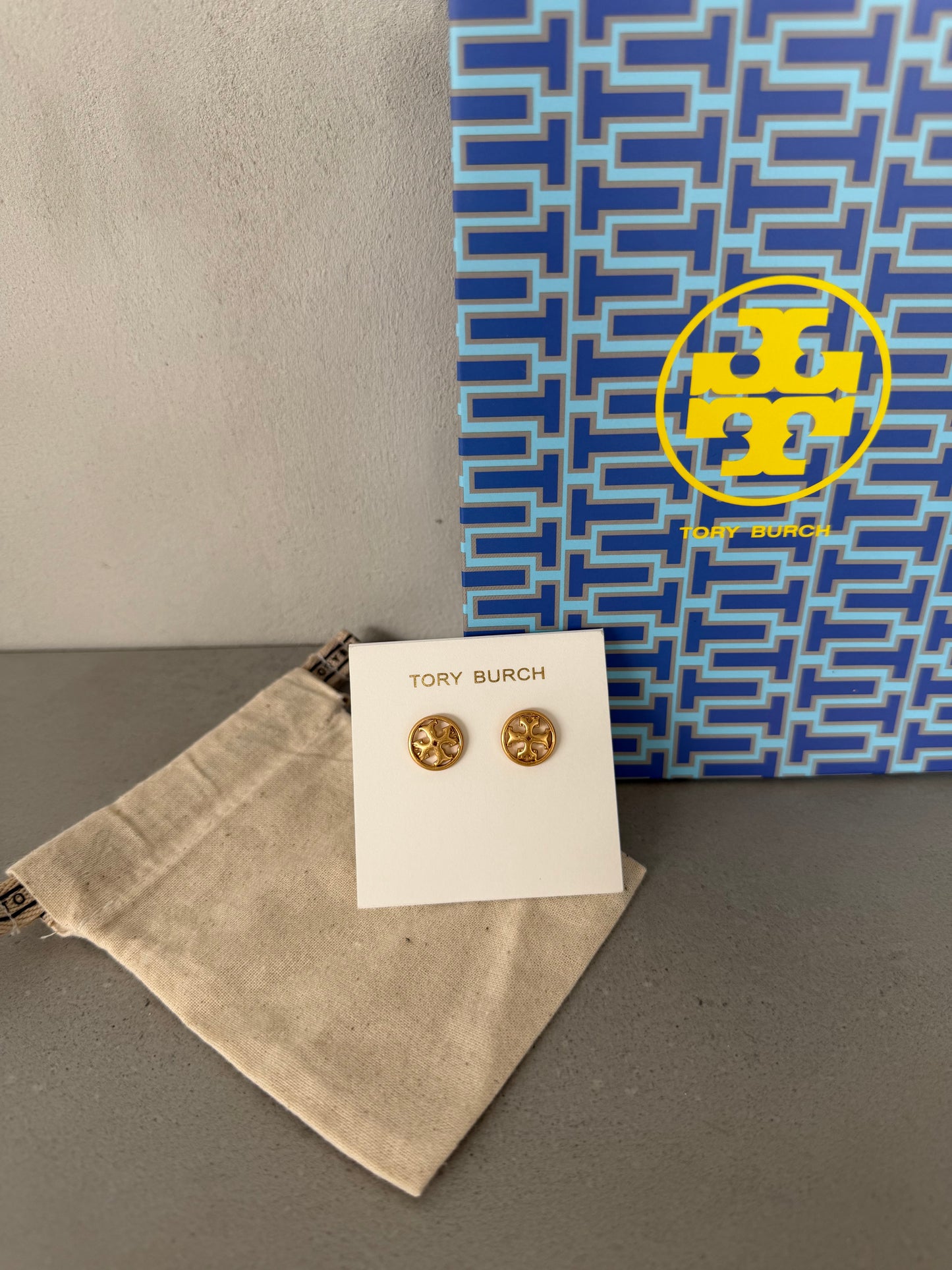 Aretes TB dorados pequeños con logo redondo decorativo