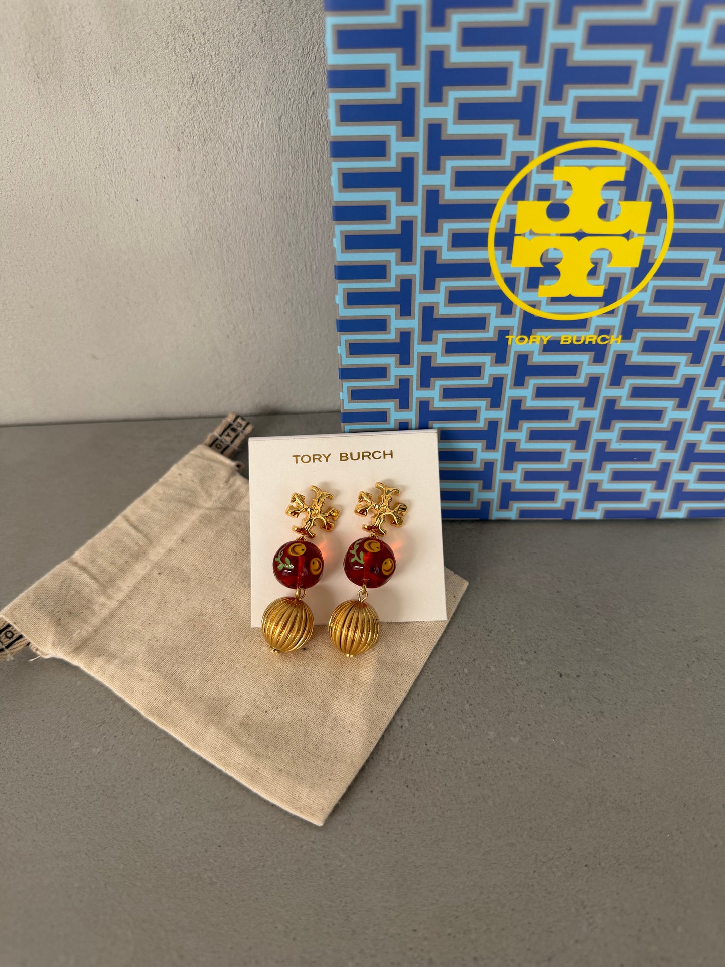 Aretes TB dorados con detalles rojos y colgante esférico