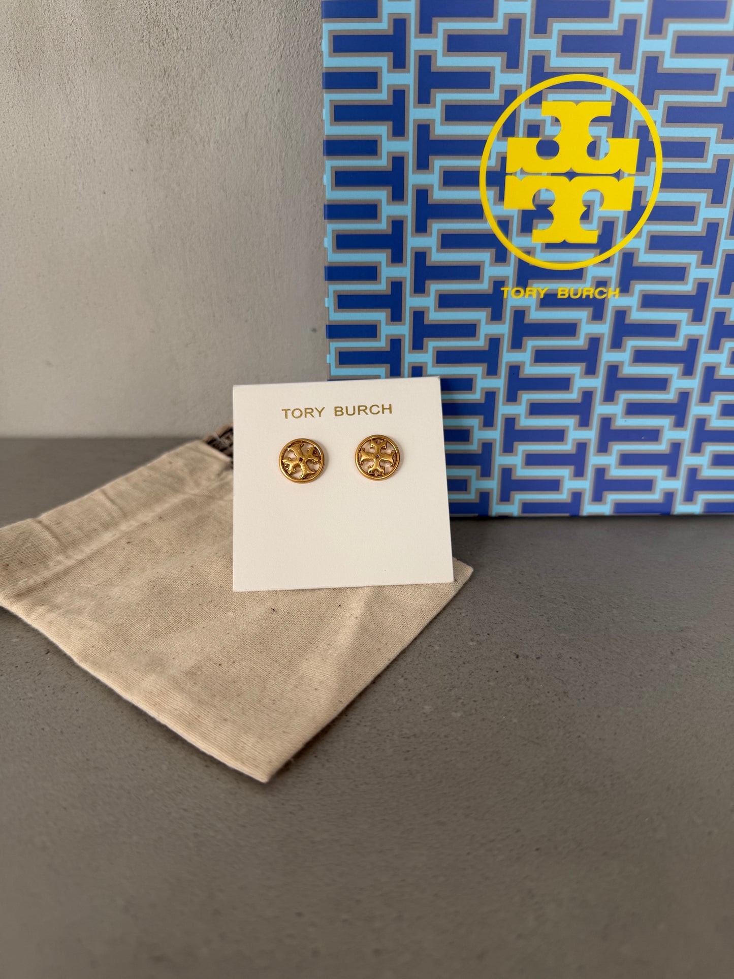 Aretes TB dorados pequeños con logo redondo decorativo