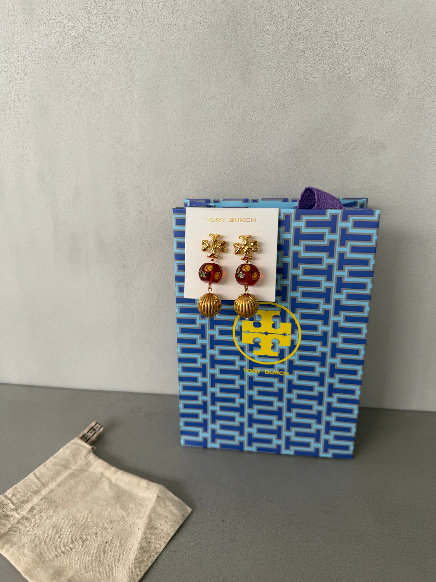 Aretes TB dorados con detalles rojos y colgante esférico