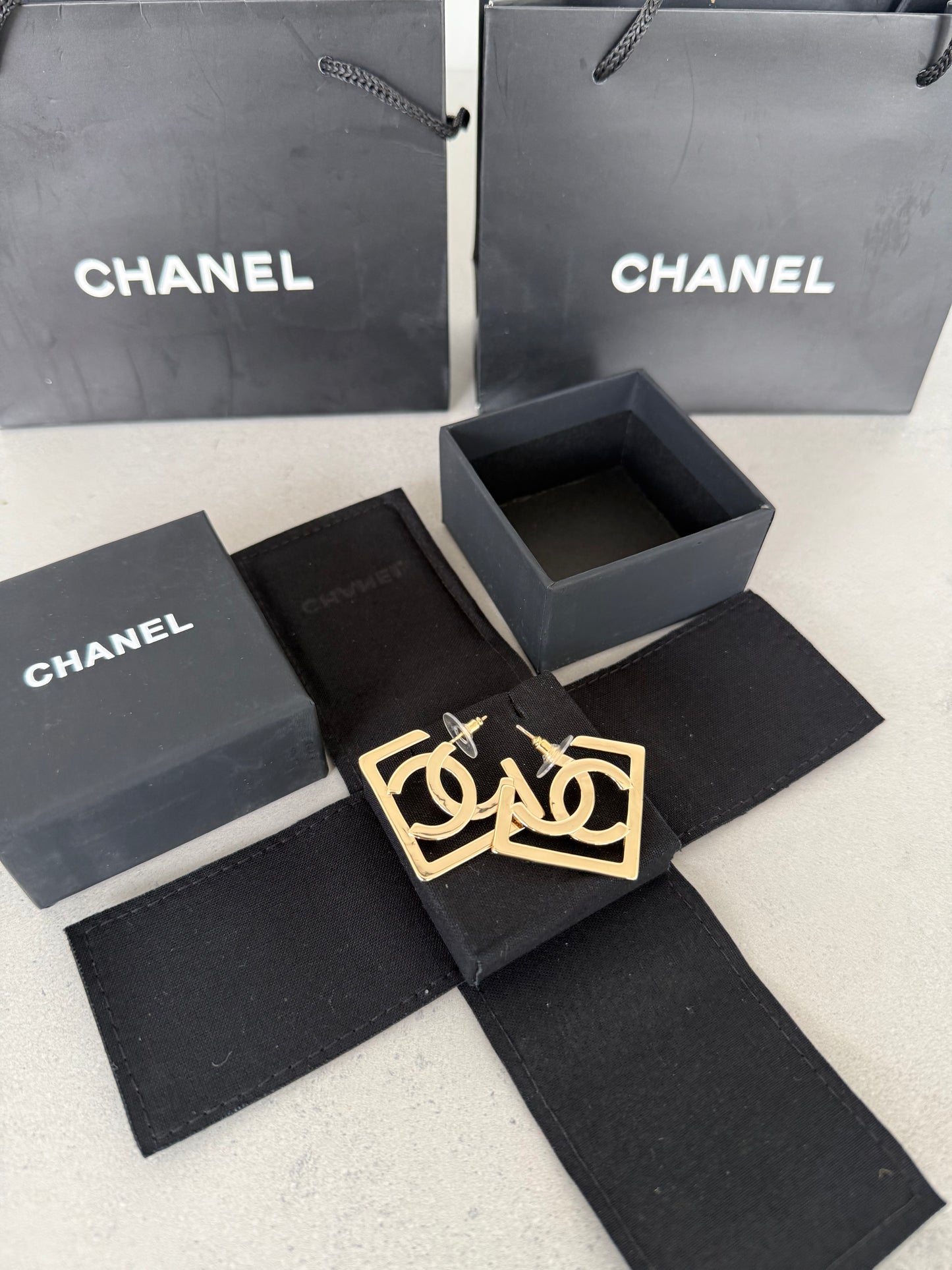 Aretes CC logo dorado en marco geométrico