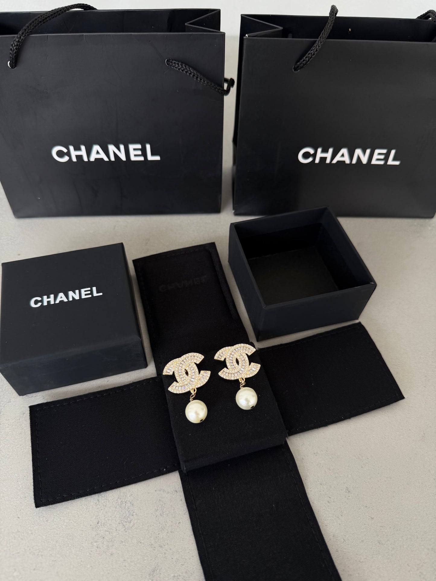 Aretes CC dorados con diamantes y perla colgante