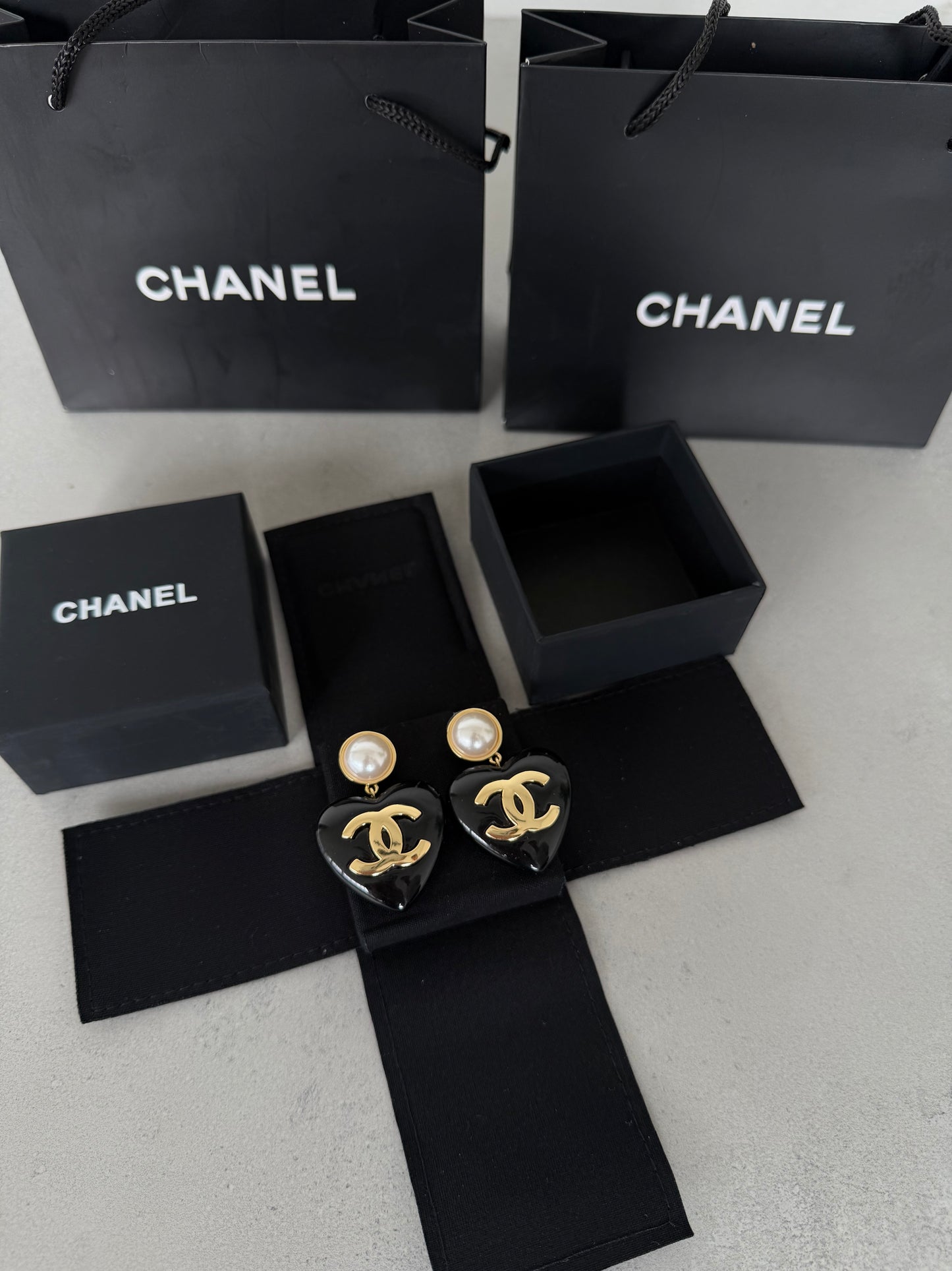 Aretes CC corazón negro con perla y logo dorado