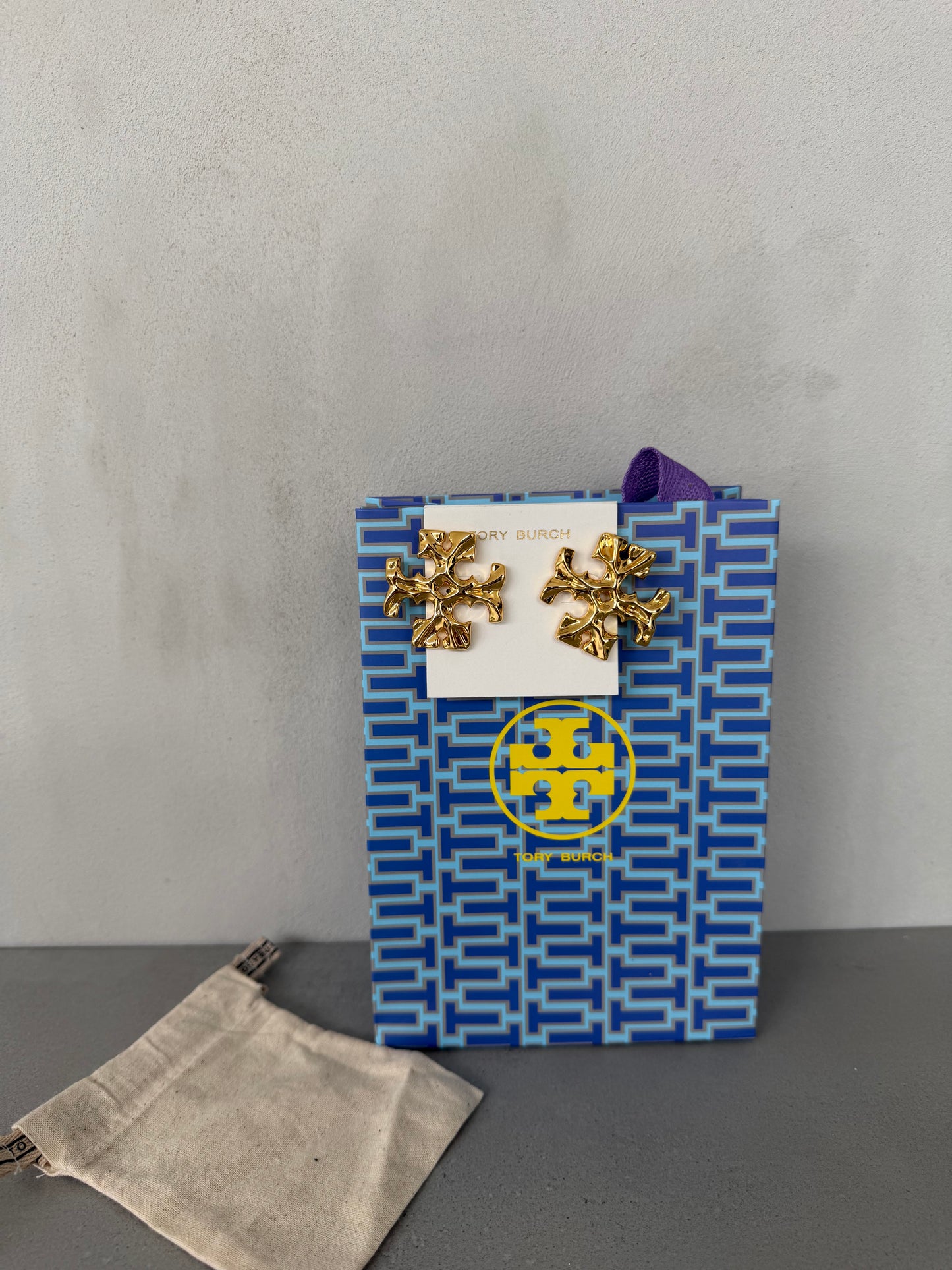 Aretes TB dorados con diseño de logo texturizado