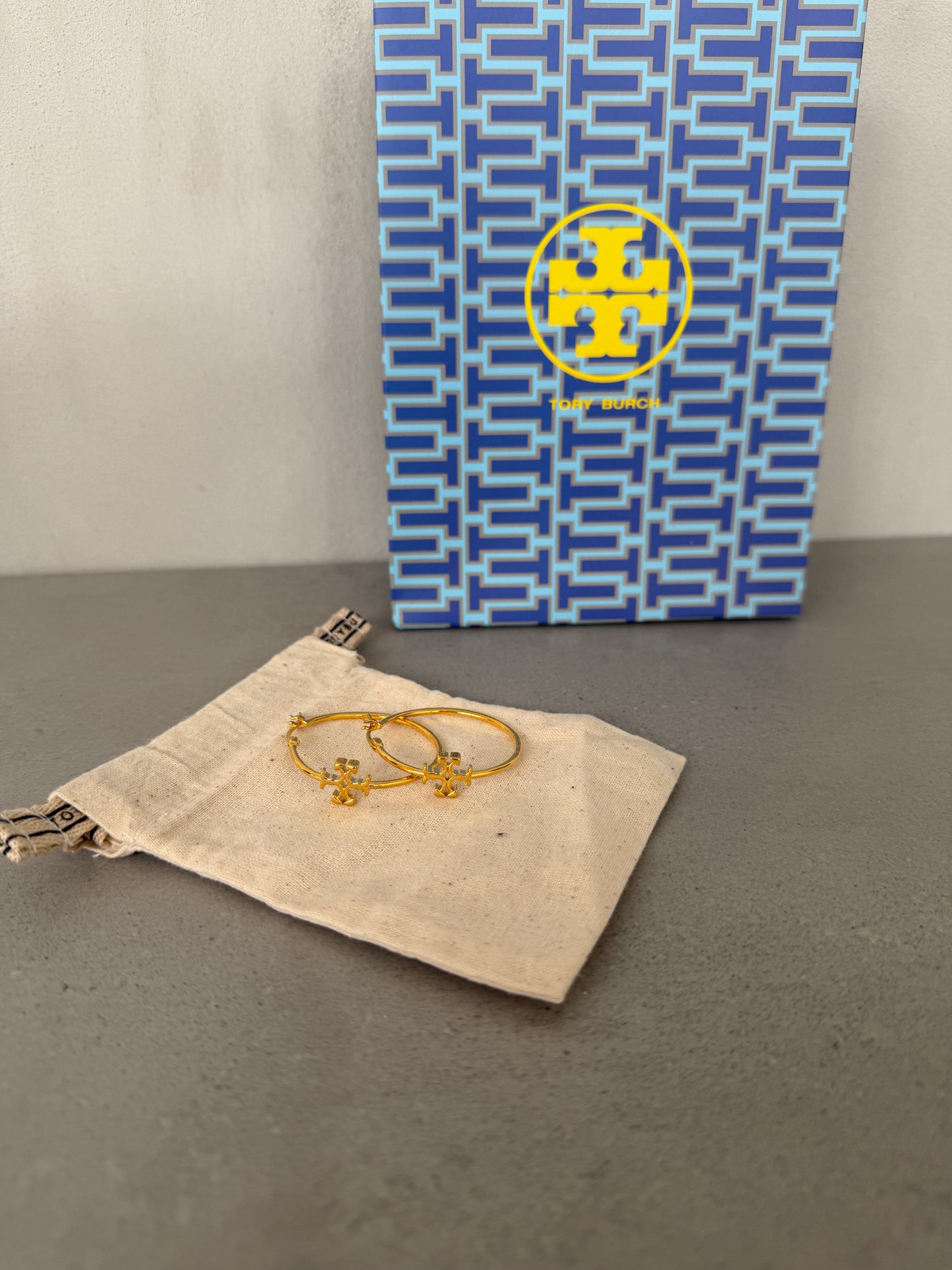 Aretes TB dorados tipo argolla con detalle de logo pequeño