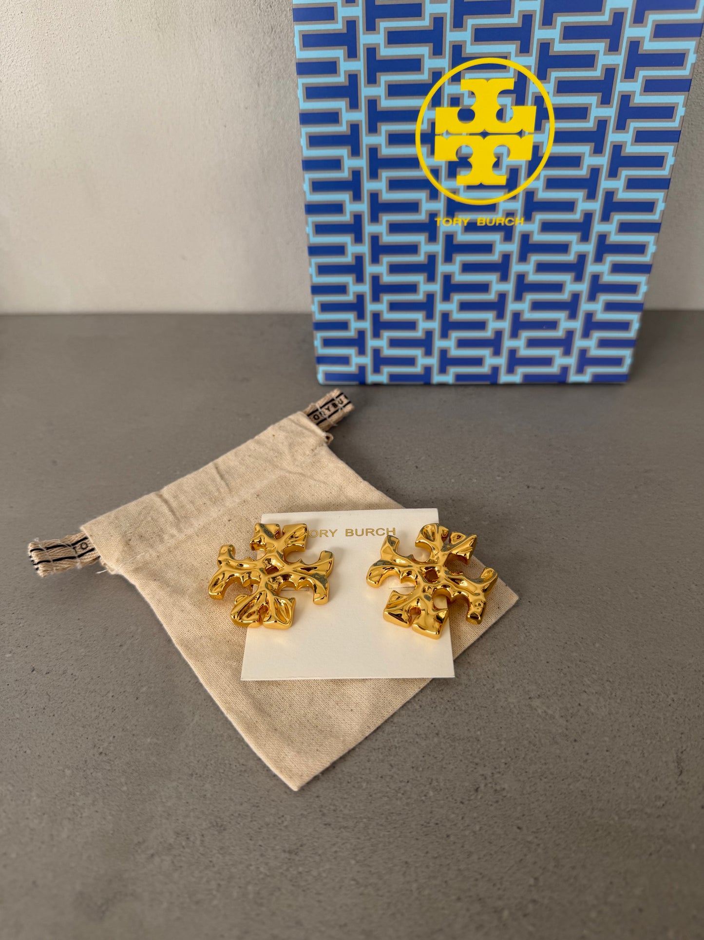 Aretes TB dorados con diseño de logo texturizado