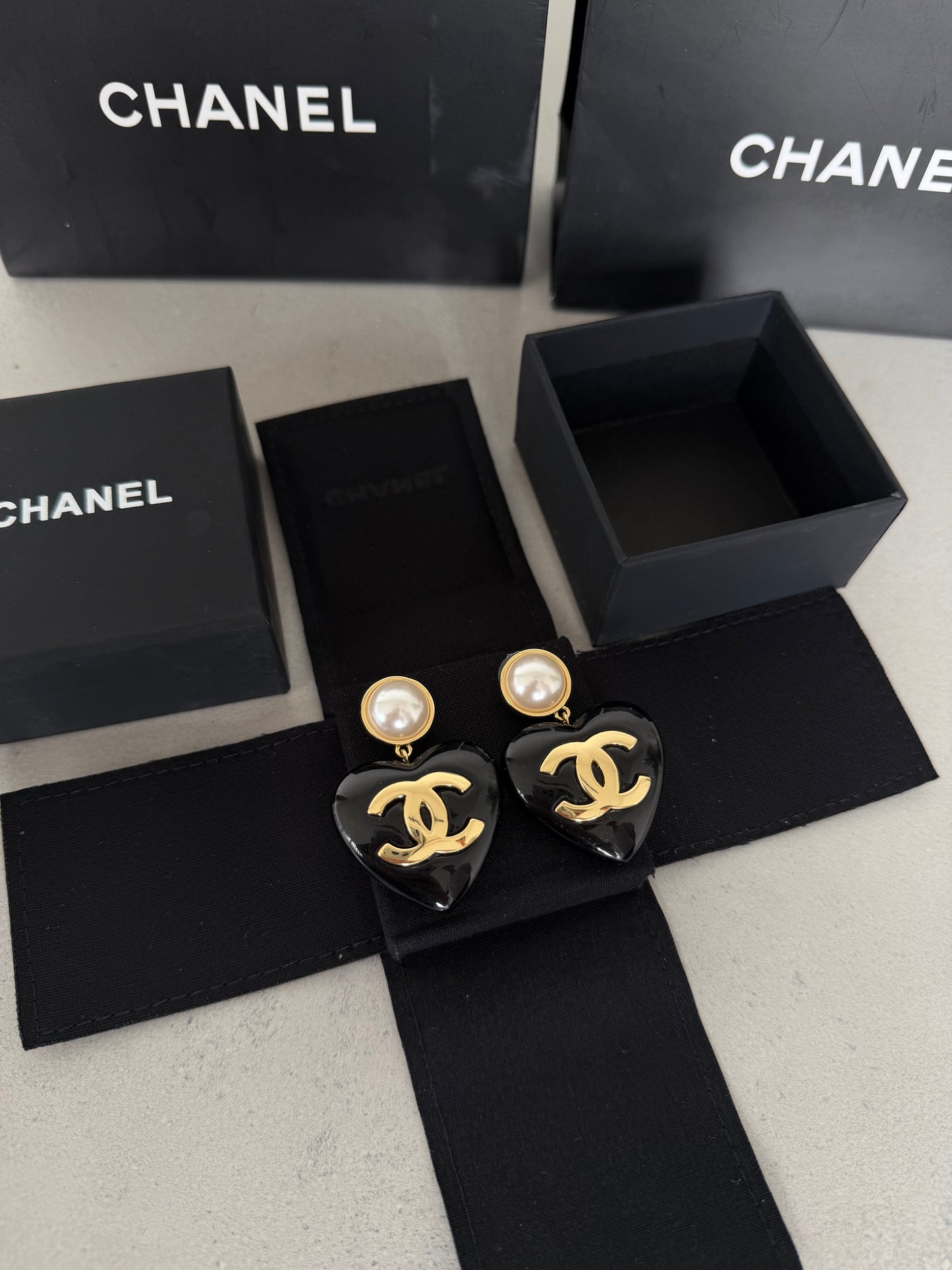Aretes CC corazón negro con perla y logo dorado