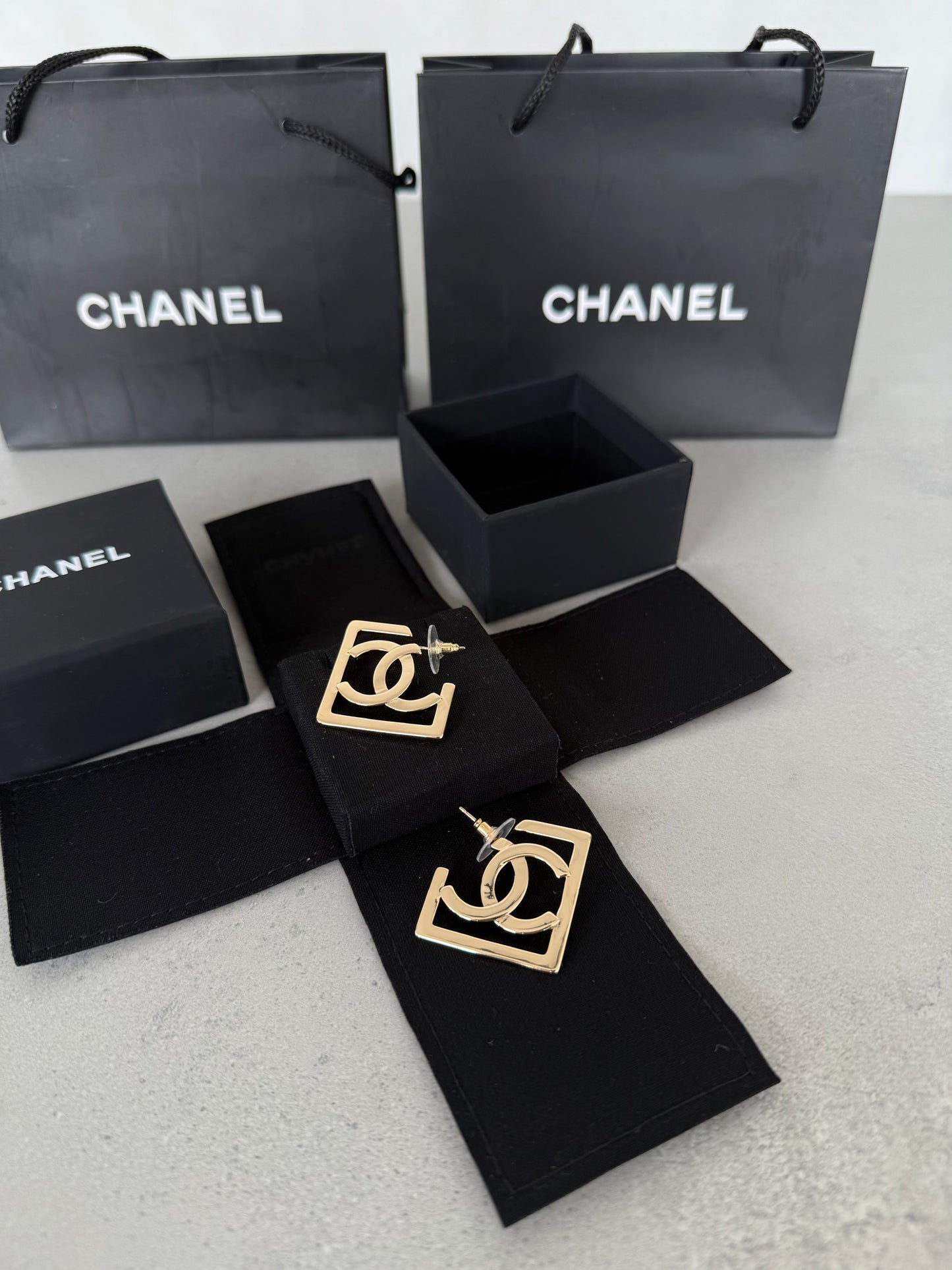 Aretes CC logo dorado en marco geométrico