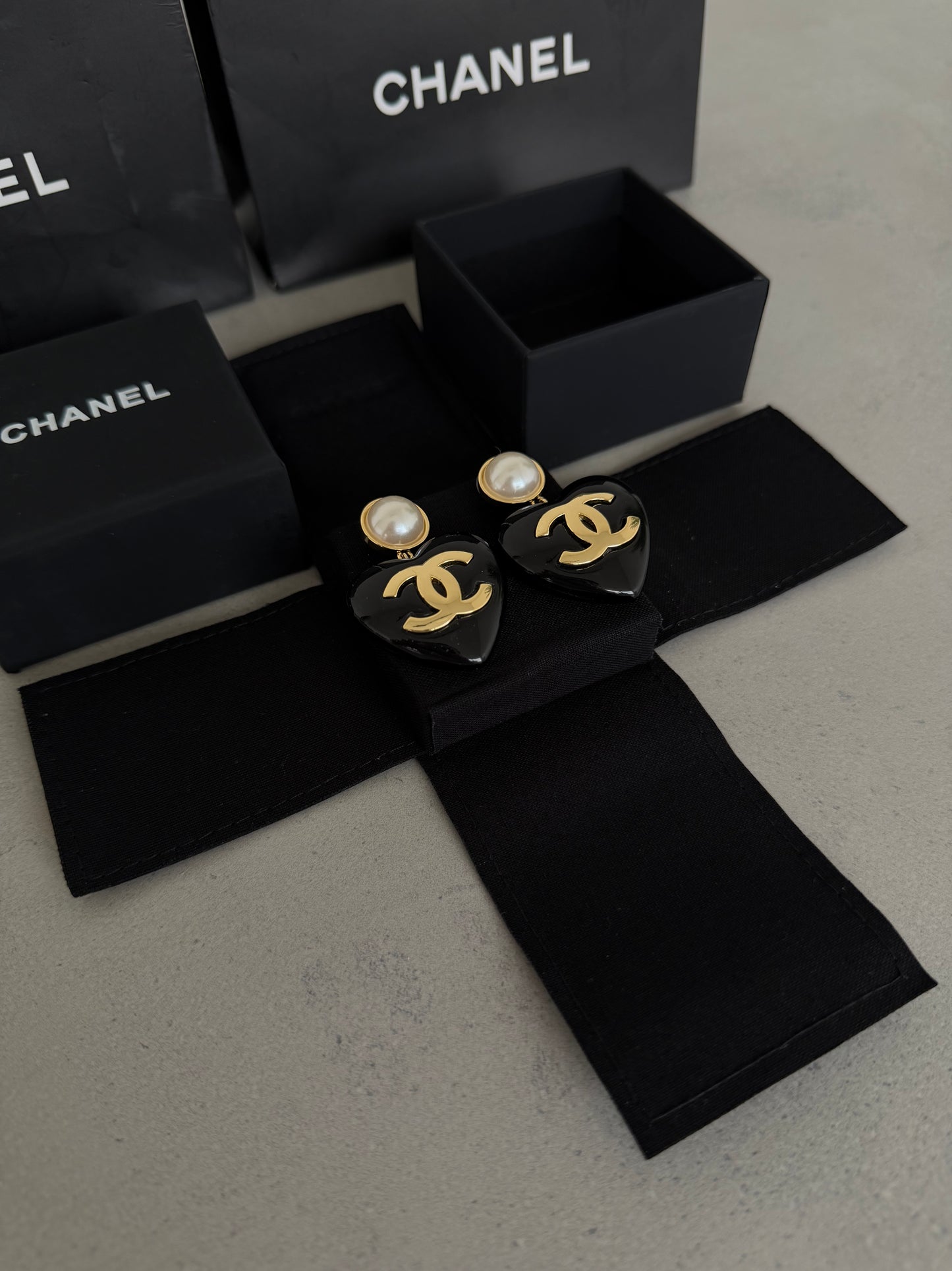 Aretes CC corazón negro con perla y logo dorado