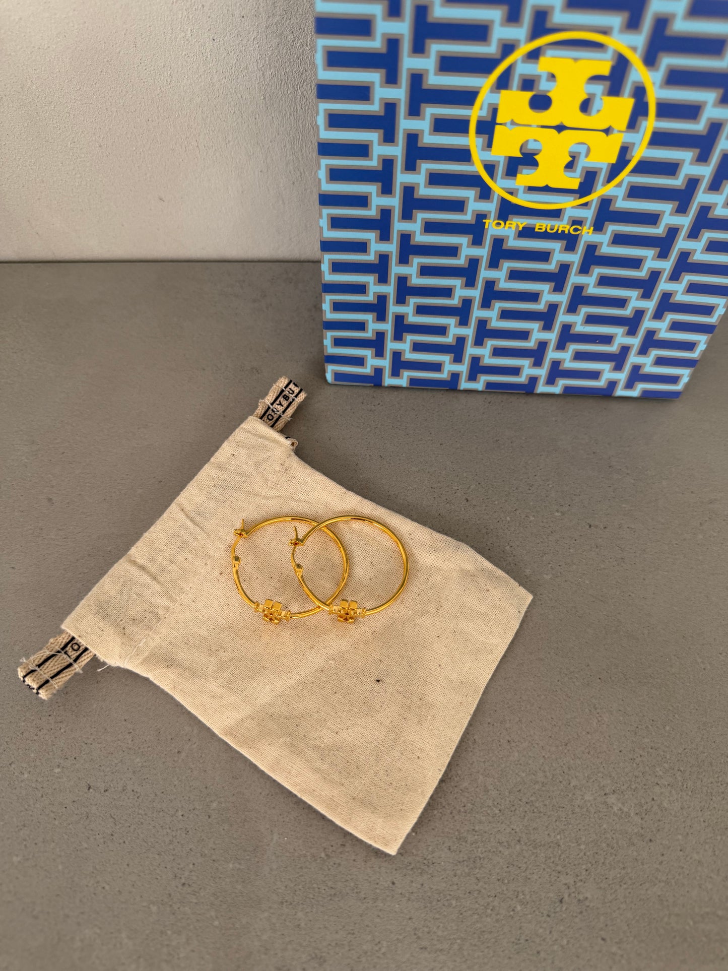 Aretes TB dorados tipo argolla con detalle de logo pequeño