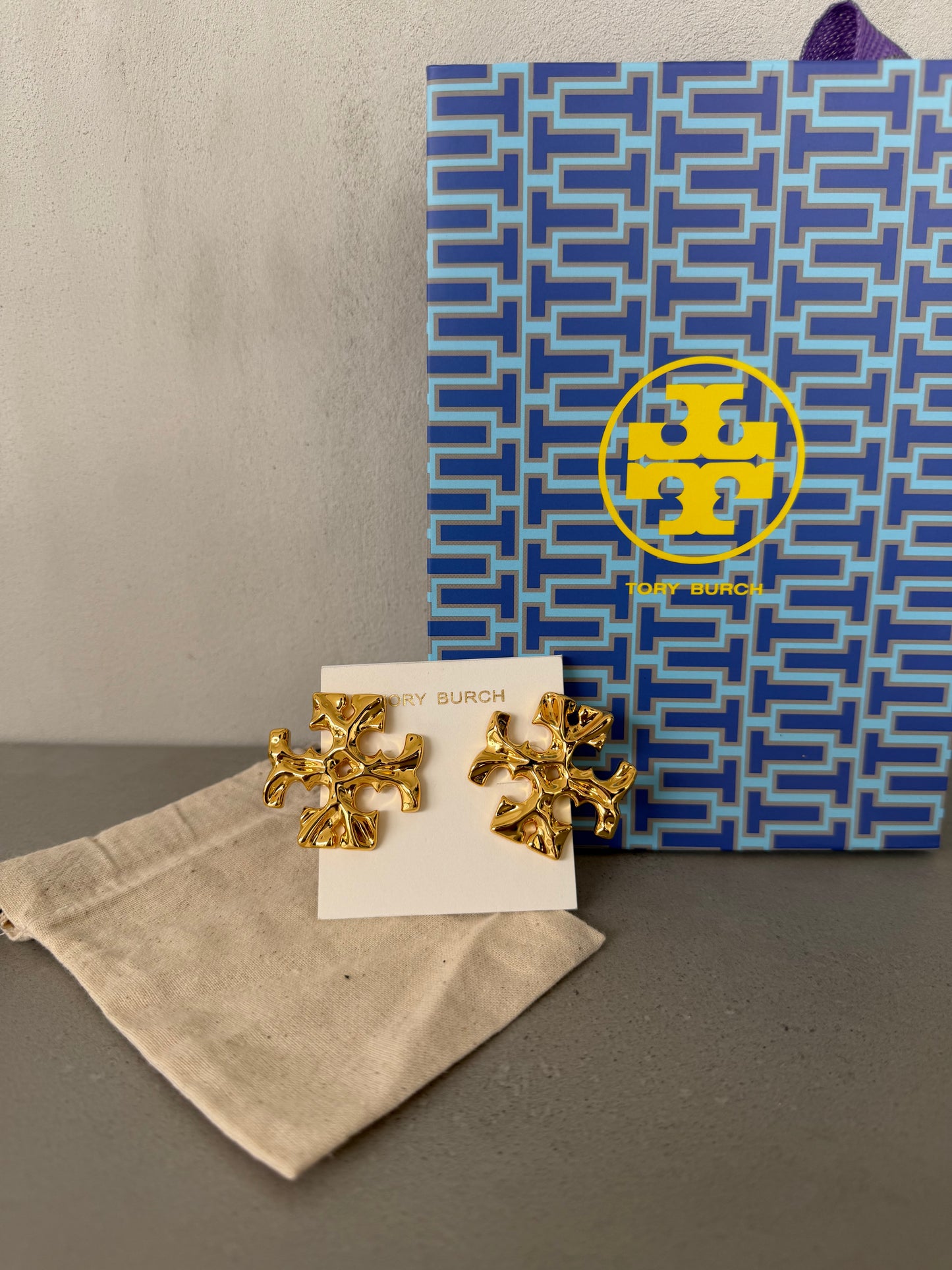 Aretes TB dorados con diseño de logo texturizado