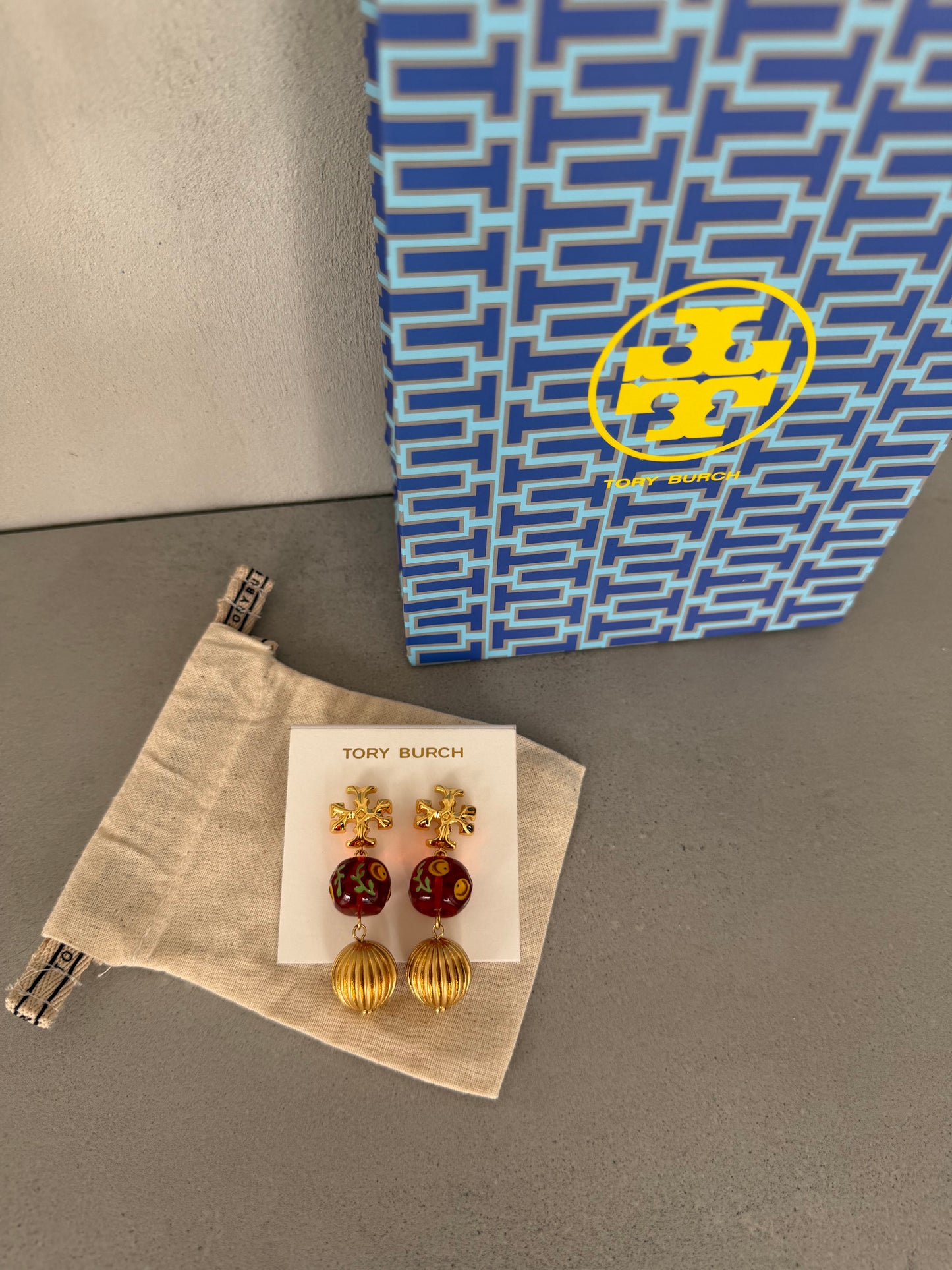 Aretes TB dorados con detalles rojos y colgante esférico